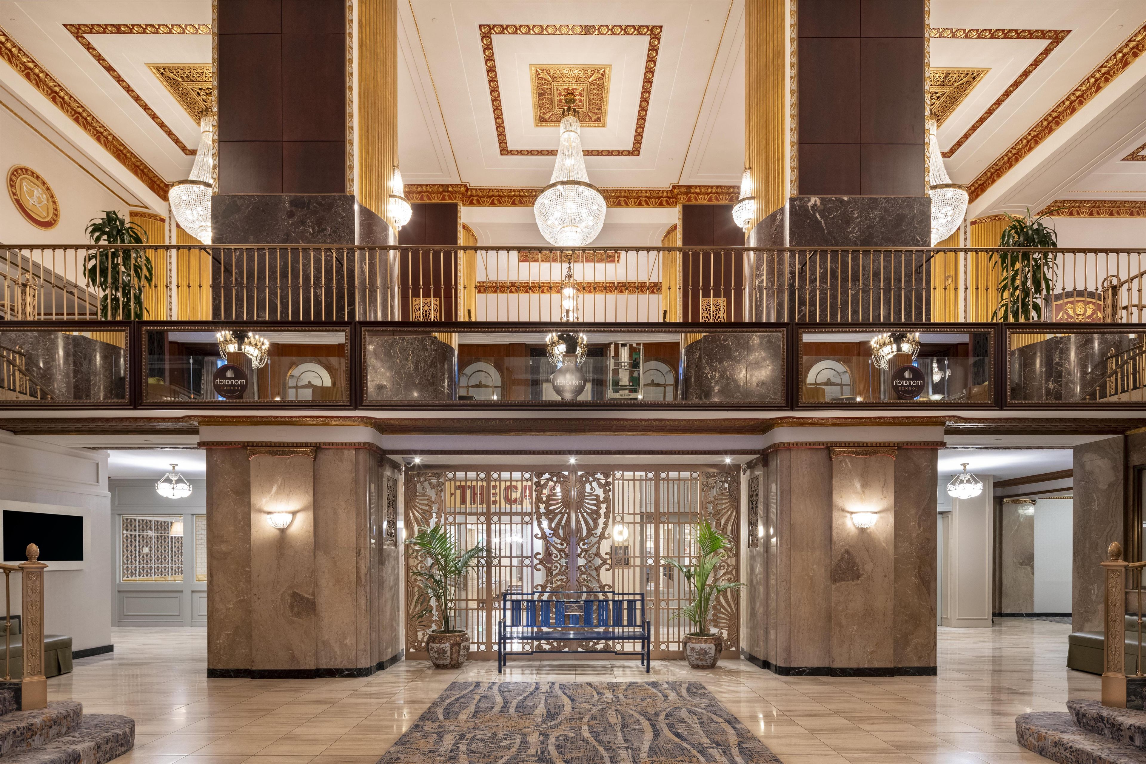 A grand lobby with a marble floor, a central bench, and a decorative wall with a chandelier.