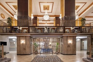 A grand lobby with a marble floor, a central bench, and a decorative wall with a chandelier. - Hilton Milwaukee (Milwaukee)
