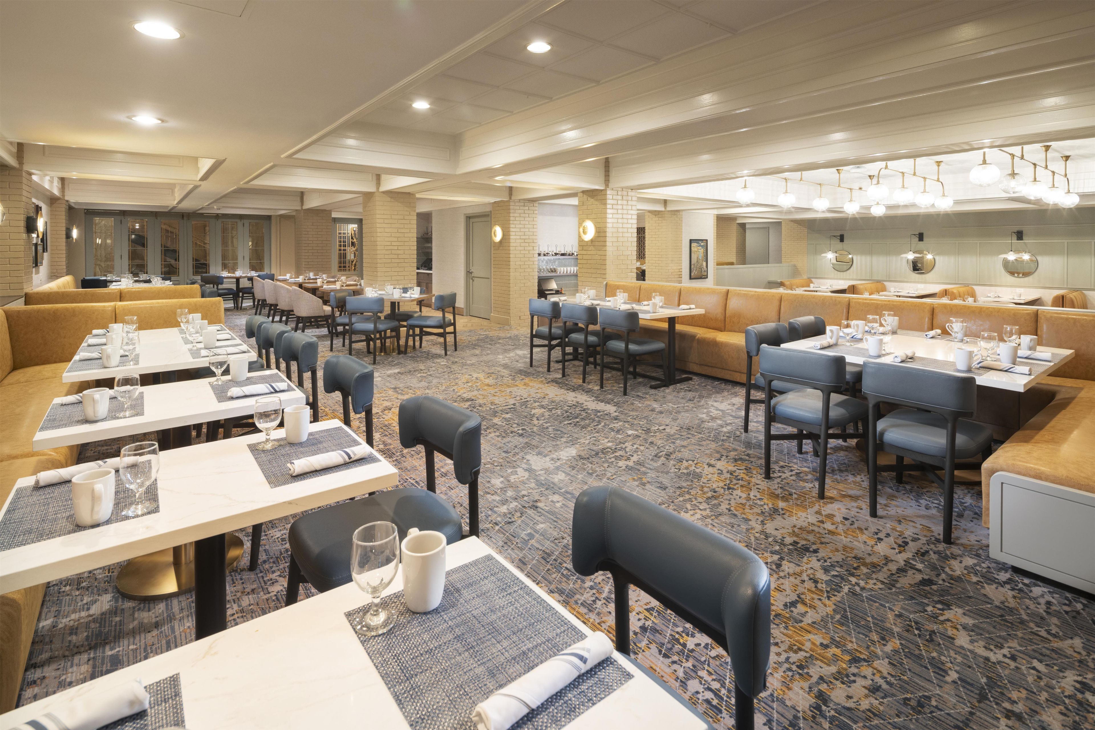 A spacious restaurant with multiple seating areas, including booths and tables, and a patterned carpet.