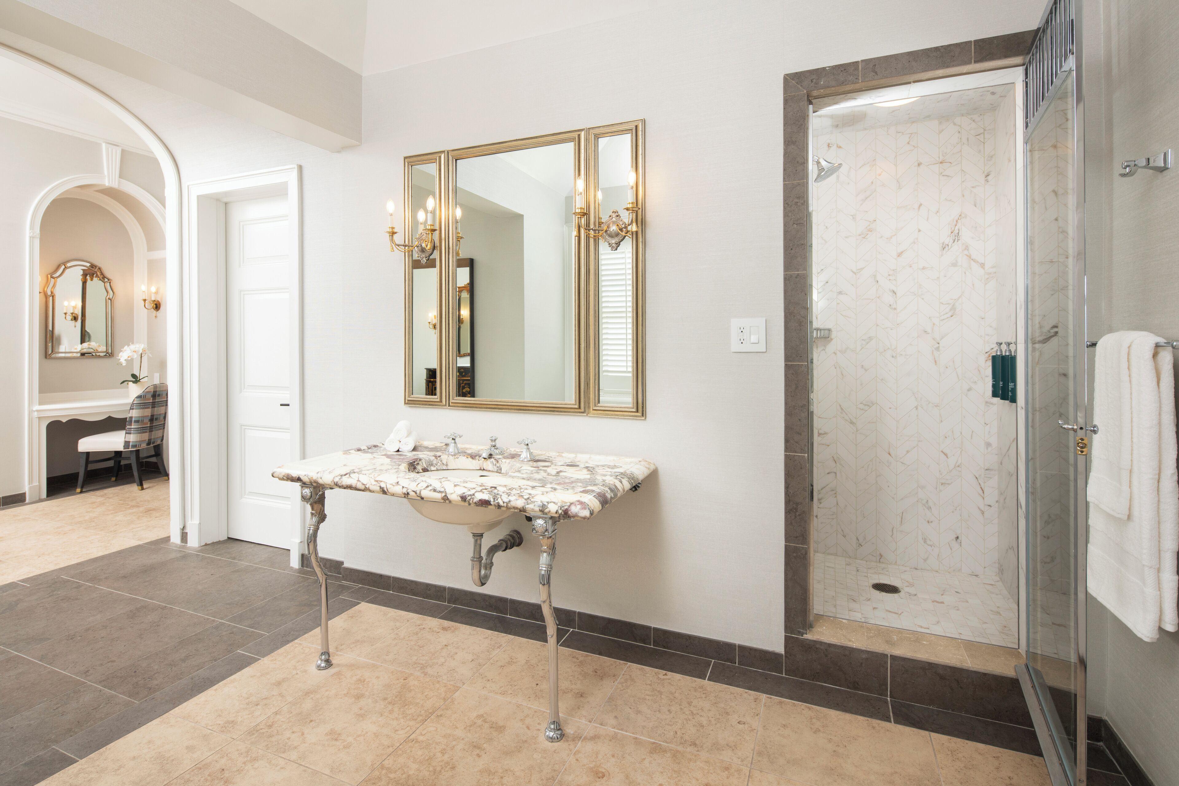 Un bagno con lavabo in marmo, uno specchio grande e cabina doccia in vetro.