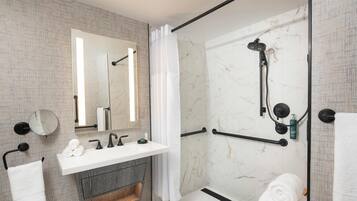 A modern bathroom with a glass-enclosed shower, a white sink, and a large mirror.