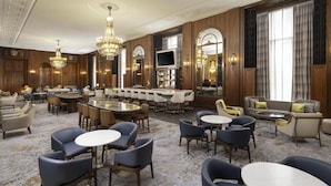 Eine großzügige Hotelhalle mit verschiedenen Sitzbereichen, einer Bar und einem Fernsehbildschirm.