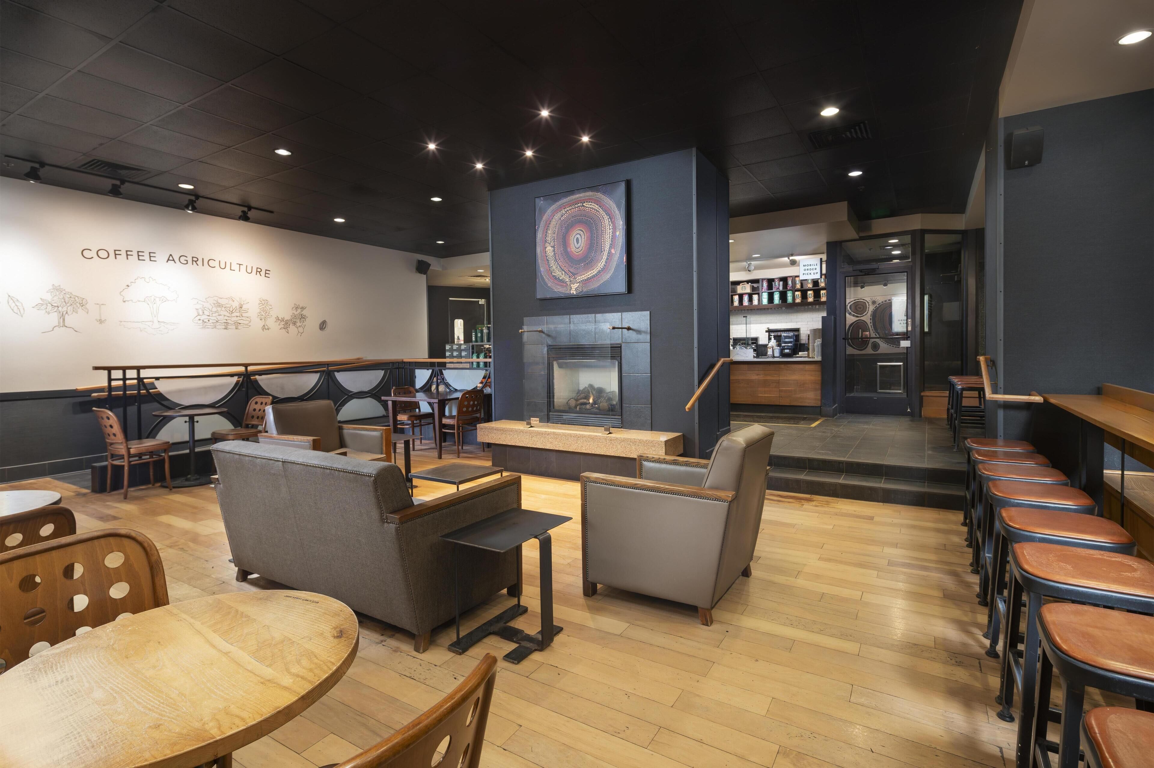 A coffee shop interior with seating, a fireplace, and a wall with coffee-related illustrations.