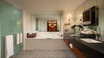 Un baño moderno con un espejo grande, dos lavamanos, una bañera y un tocador con televisor.