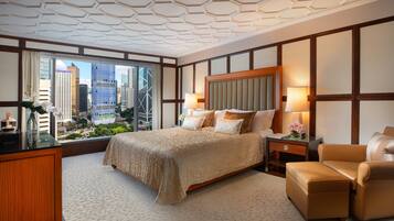 A hotel room with a large bed, a desk, a chair, and a view of the cityscape.