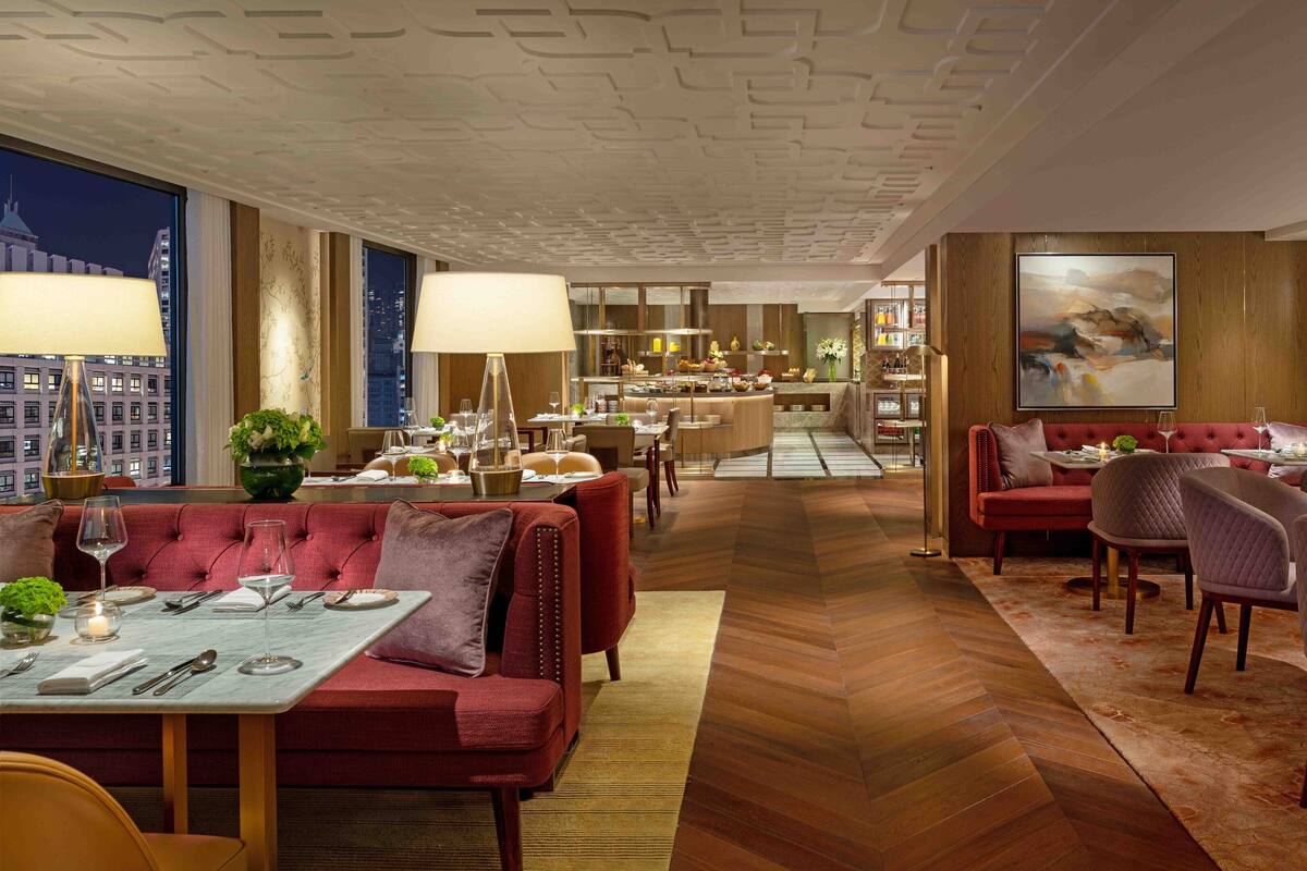 A modern hotel lobby with a dining area, a bar, and a view of the cityscape.