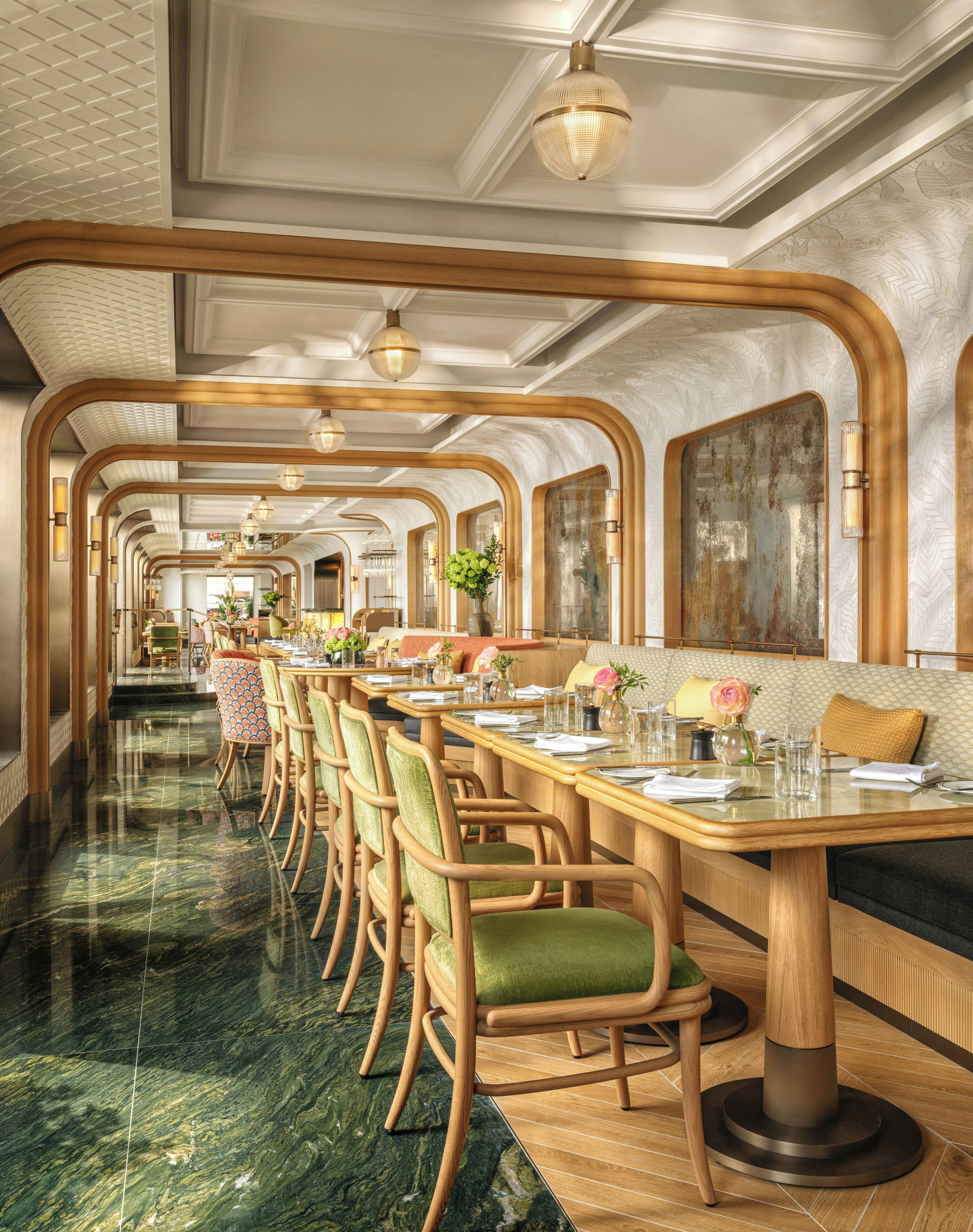 A restaurant with a long dining area, wooden chairs, and tables set for service.