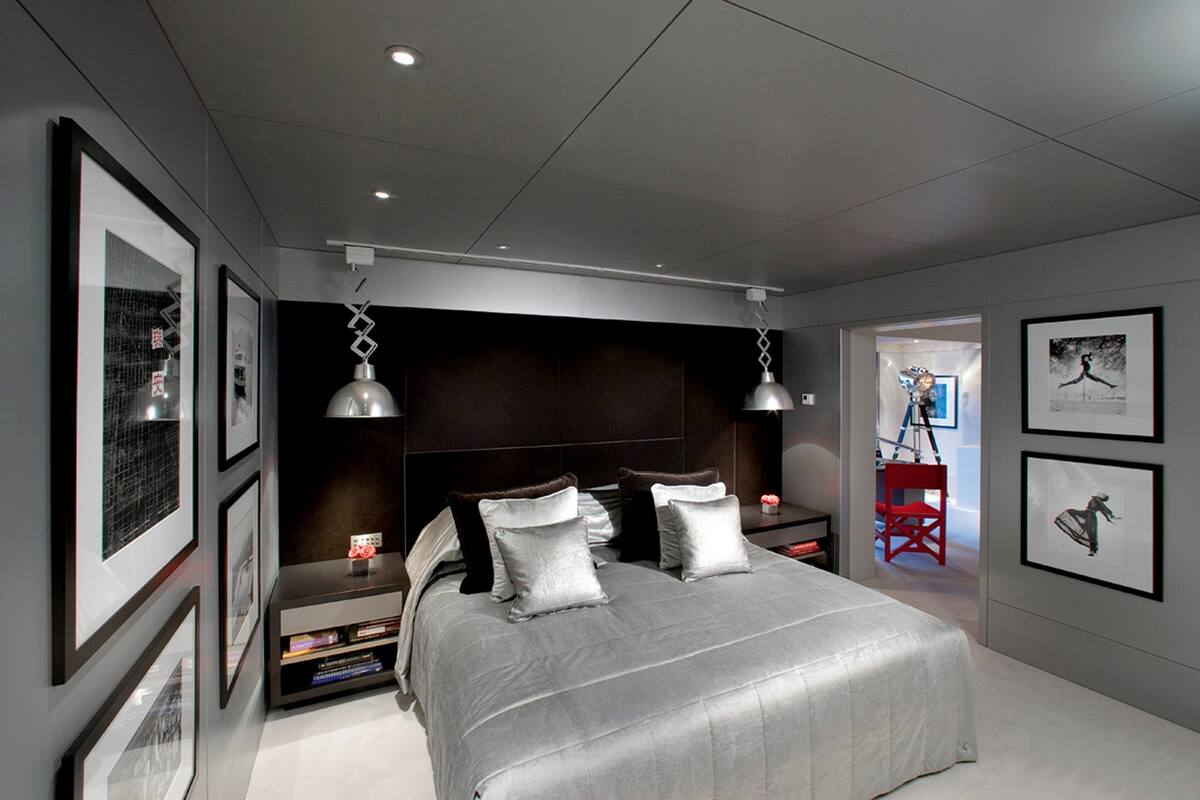 A modern bedroom with a large bed, bedside tables, and framed artwork on the walls.