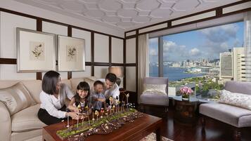 A modern living room with a city view, a large wooden coffee table with chocolate treats, and a comfortable seating area.