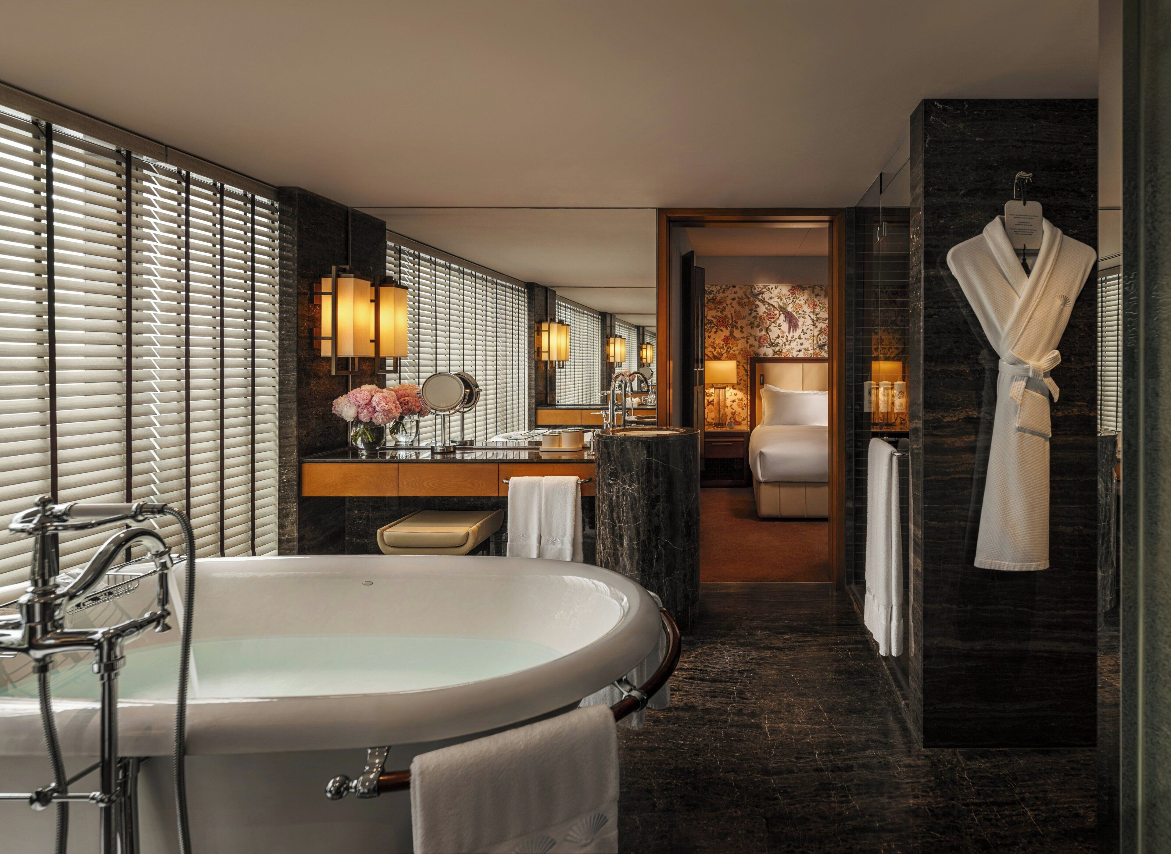 Ein modernes Badezimmer mit einer freistehenden Badewanne, einem Waschtisch mit Spiegel und einem Bademantel, der an der Wand hängt.