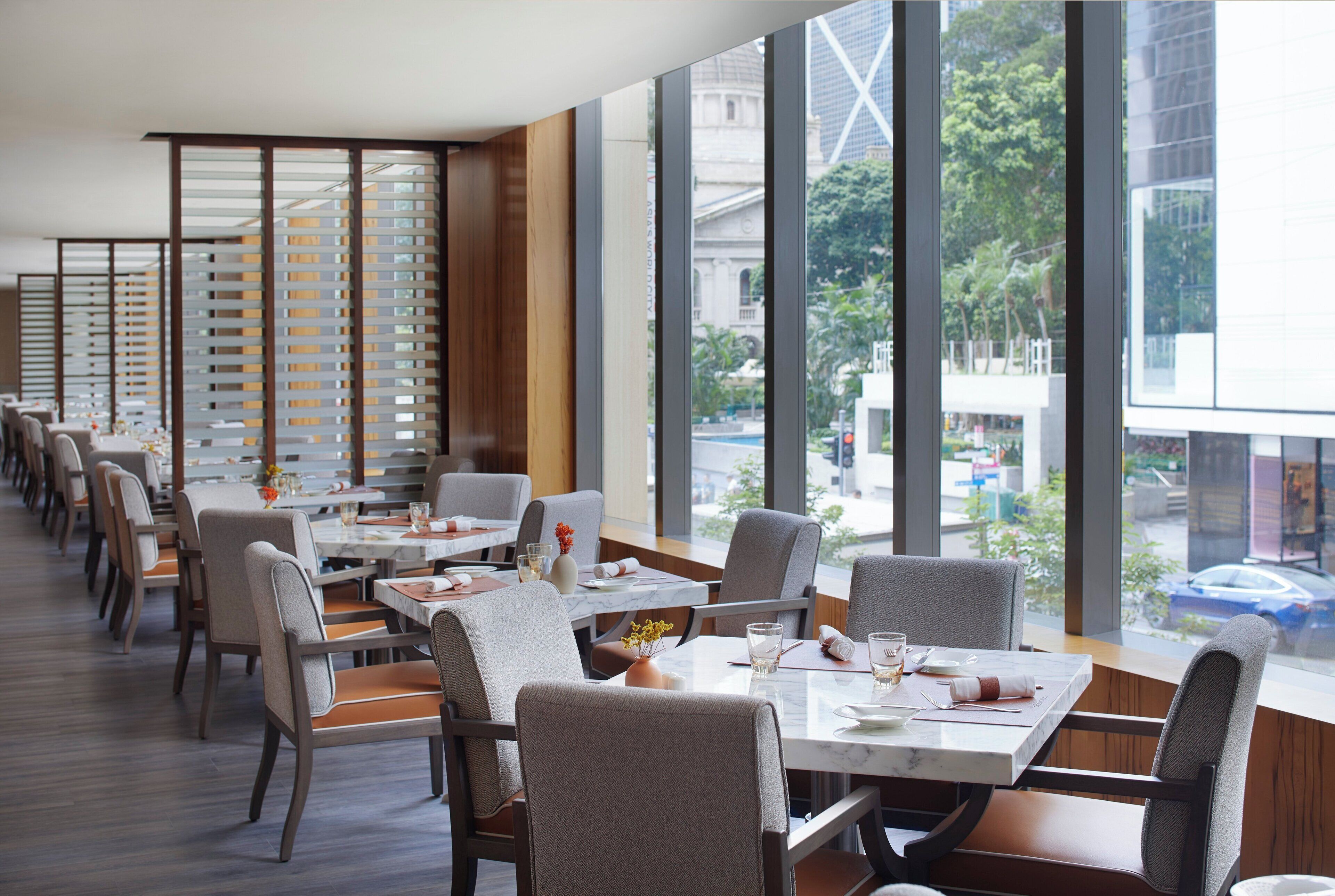 Un restaurant moderne doté d’une grande salle à manger, de larges fenêtres et d’une vue sur la ville.