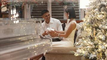 A couple sitting by a Christmas tree in a well-lit indoor setting with a modern, clean design.