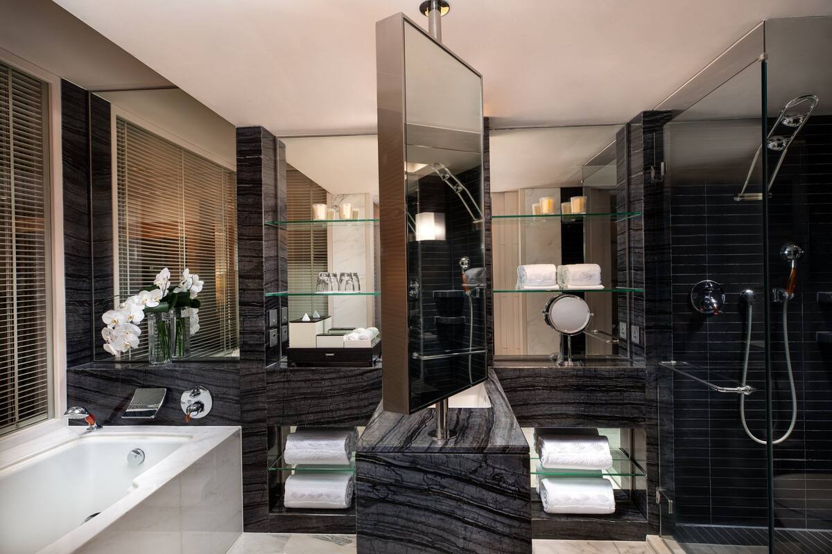 A modern bathroom with a glass-enclosed shower, a large mirror, and marble countertops.