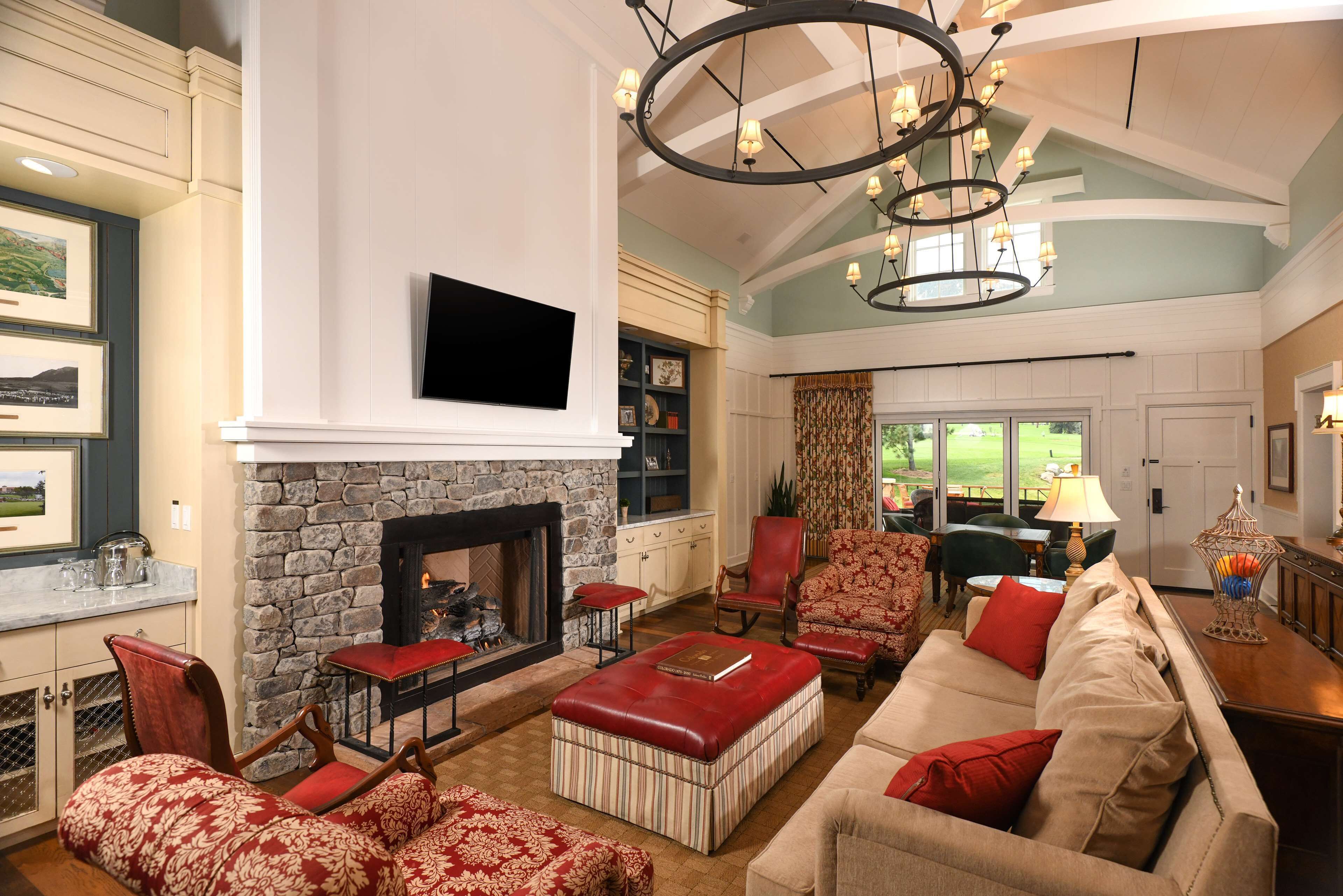 A spacious living room with a stone fireplace, comfortable seating, and a large chandelier.