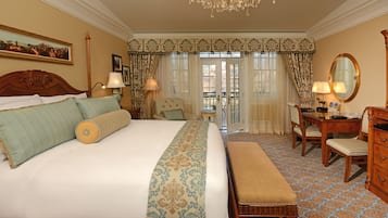 A hotel room with a large bed, a desk, a chair, and a dresser. There is a window with curtains and a view of the outside.