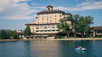 A large hotel with multiple floors and a tower, situated by a lake.