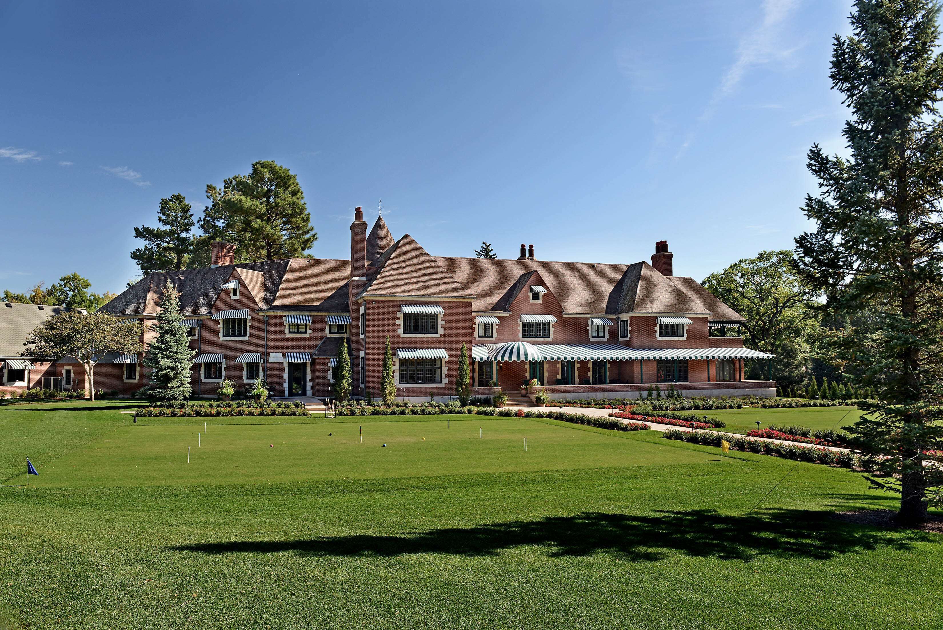 A large brick building with a well-maintained lawn and a tennis court.