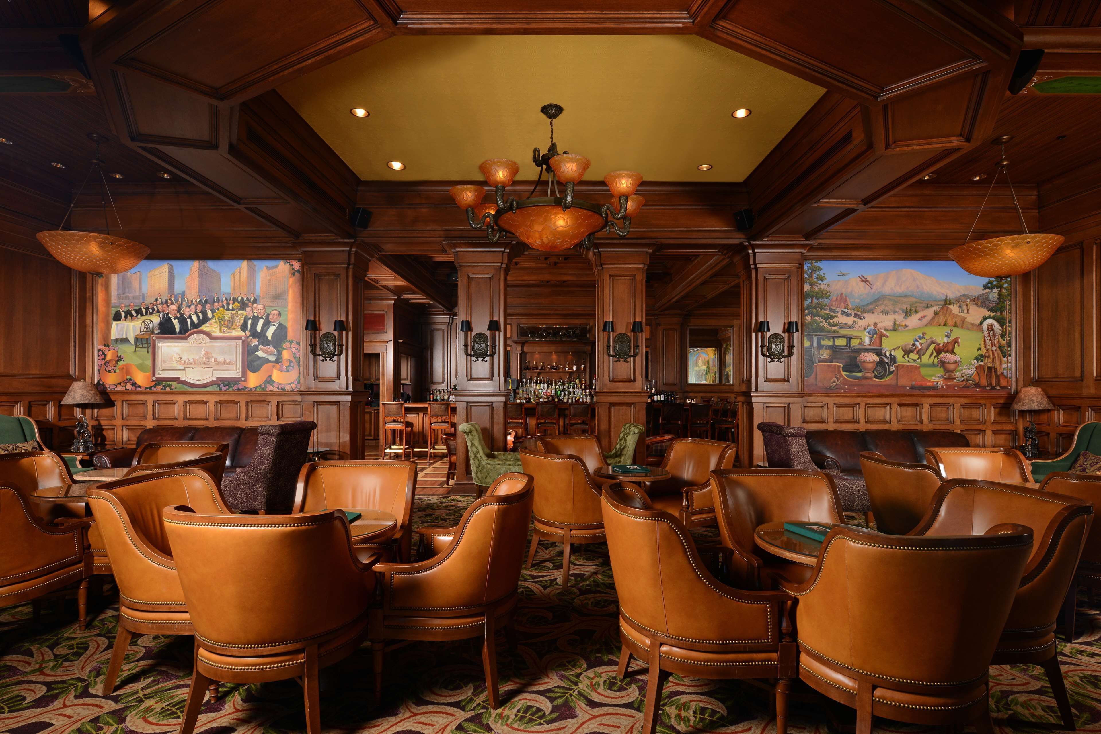 A lobby with leather chairs, a bar area, and murals on the walls.