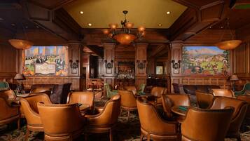 A lobby with leather chairs, a bar area, and murals on the walls.
