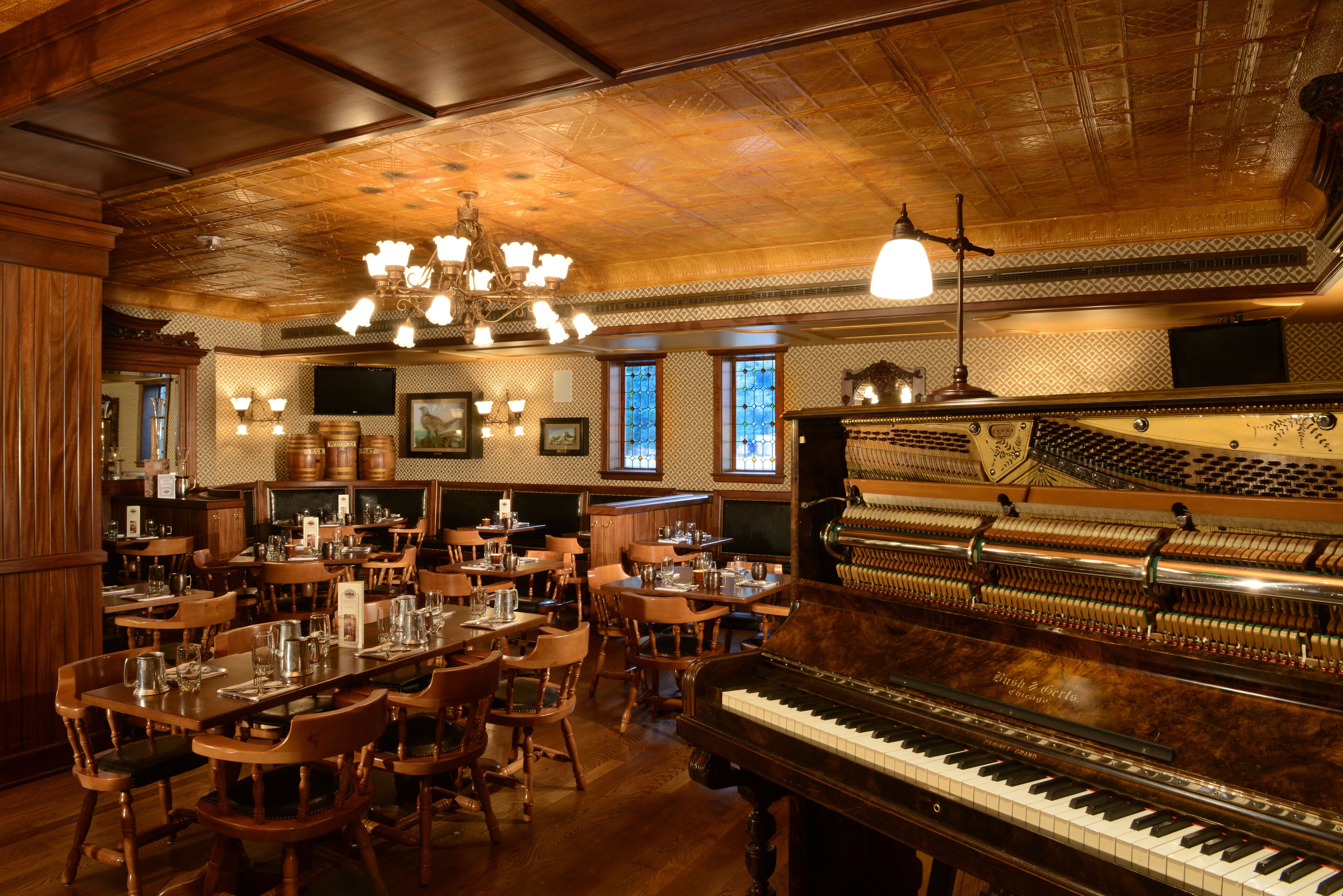A restaurant with wooden interiors, a grand piano, and multiple dining tables and chairs.
