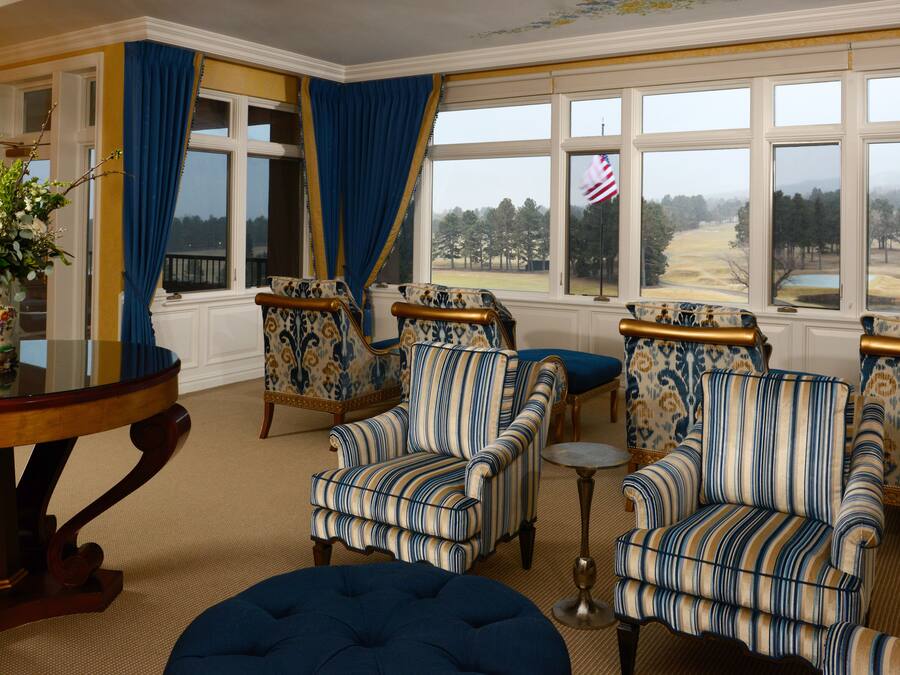 Una habitación con sillones a rayas, una mesa redonda y vistas a un paisaje a través de amplios ventanales.