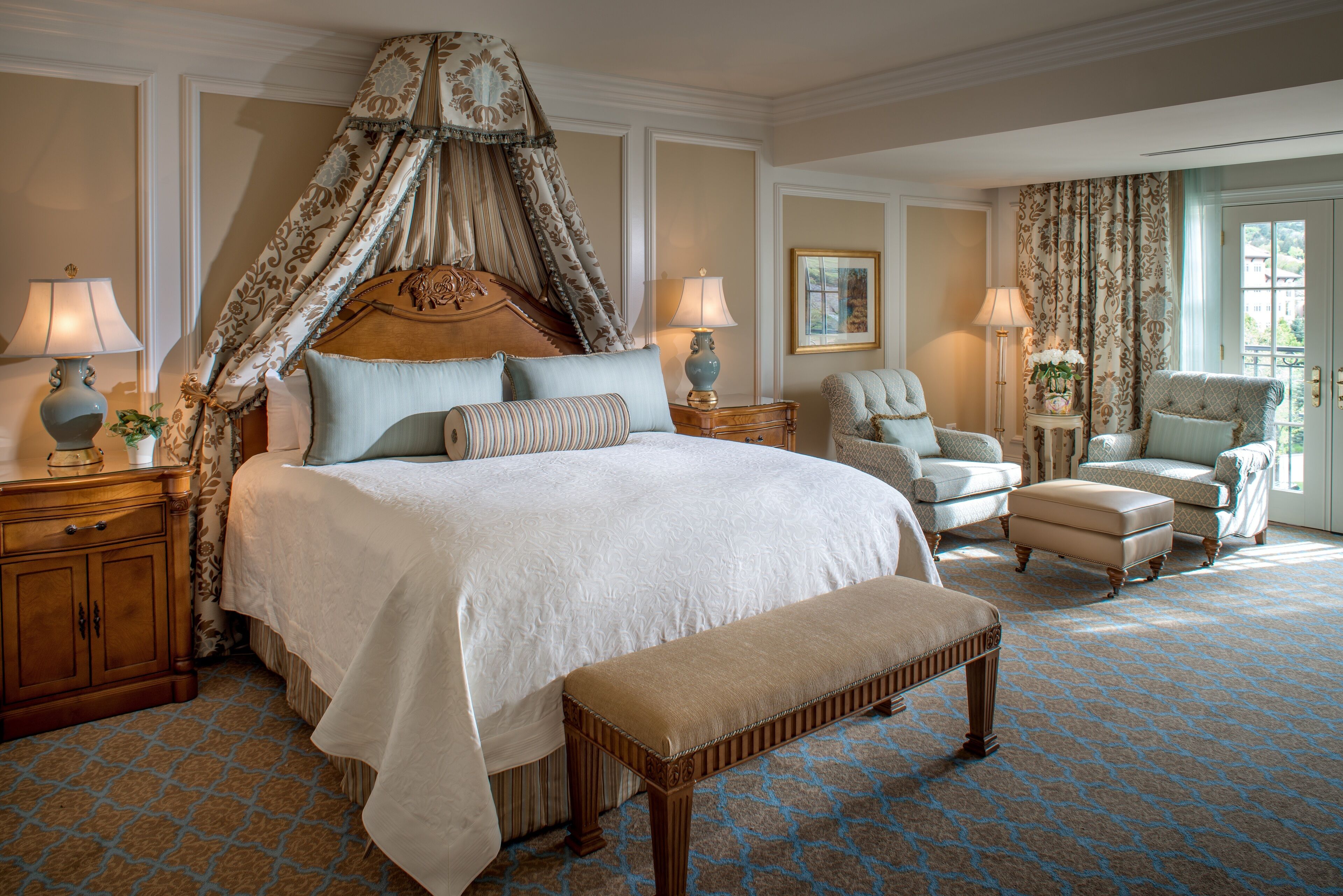 Une chambre spacieuse dotée d’un grand lit, d’un baldaquin et de plusieurs coins salon.