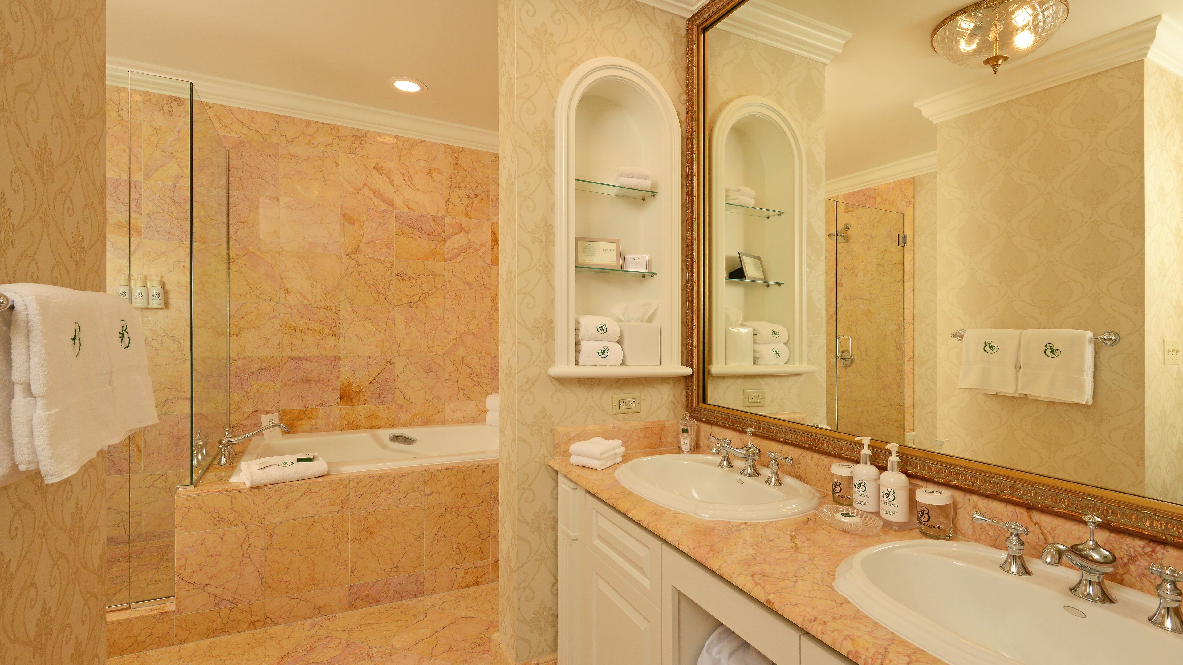 A luxurious bathroom with a marble floor, a bathtub, two sinks, and a large mirror.
