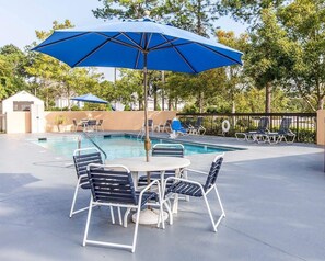 A poolside area with a table and chairs, a pool, and umbrellas. - Quality Inn At the Mall - Valdosta (Valdosta)