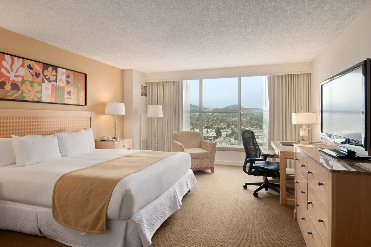 Een hotelkamer met een groot bed, een bureau, een stoel en een televisie.