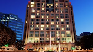 A multi-story hotel with a prominent entrance, large windows, and a flagpole. - Hilton Los Angeles North/Glendale (Glendale)