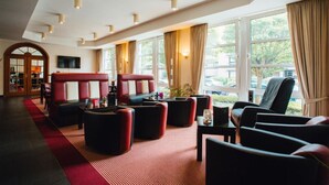 Un hall d’hôtel doté de sièges en cuir, de grandes fenêtres et d’un tapis rouge.