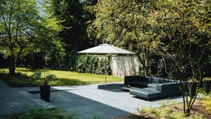 Un espace extérieur aménagé en terrasse, doté d’un mobilier contemporain et d’une pergola offrant de l’ombre.