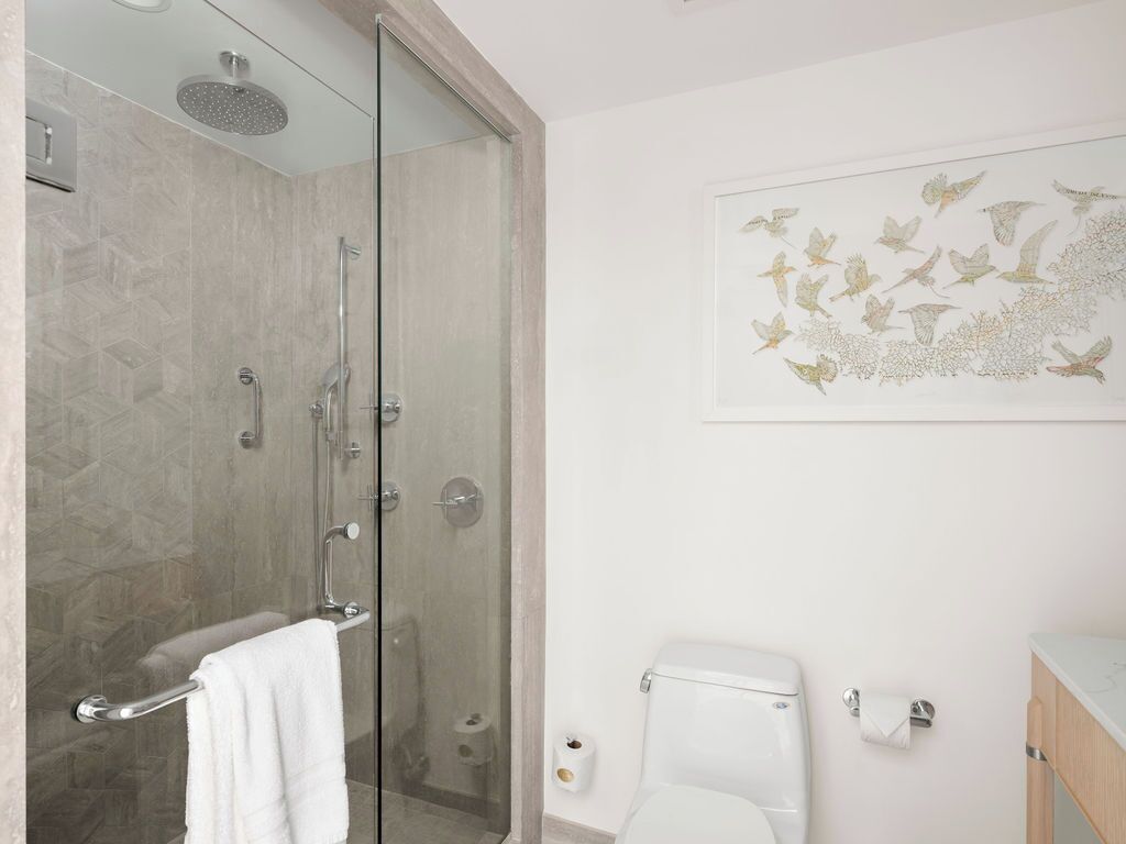 Un baño moderno con ducha de vidrio, inodoro y lavamanos.