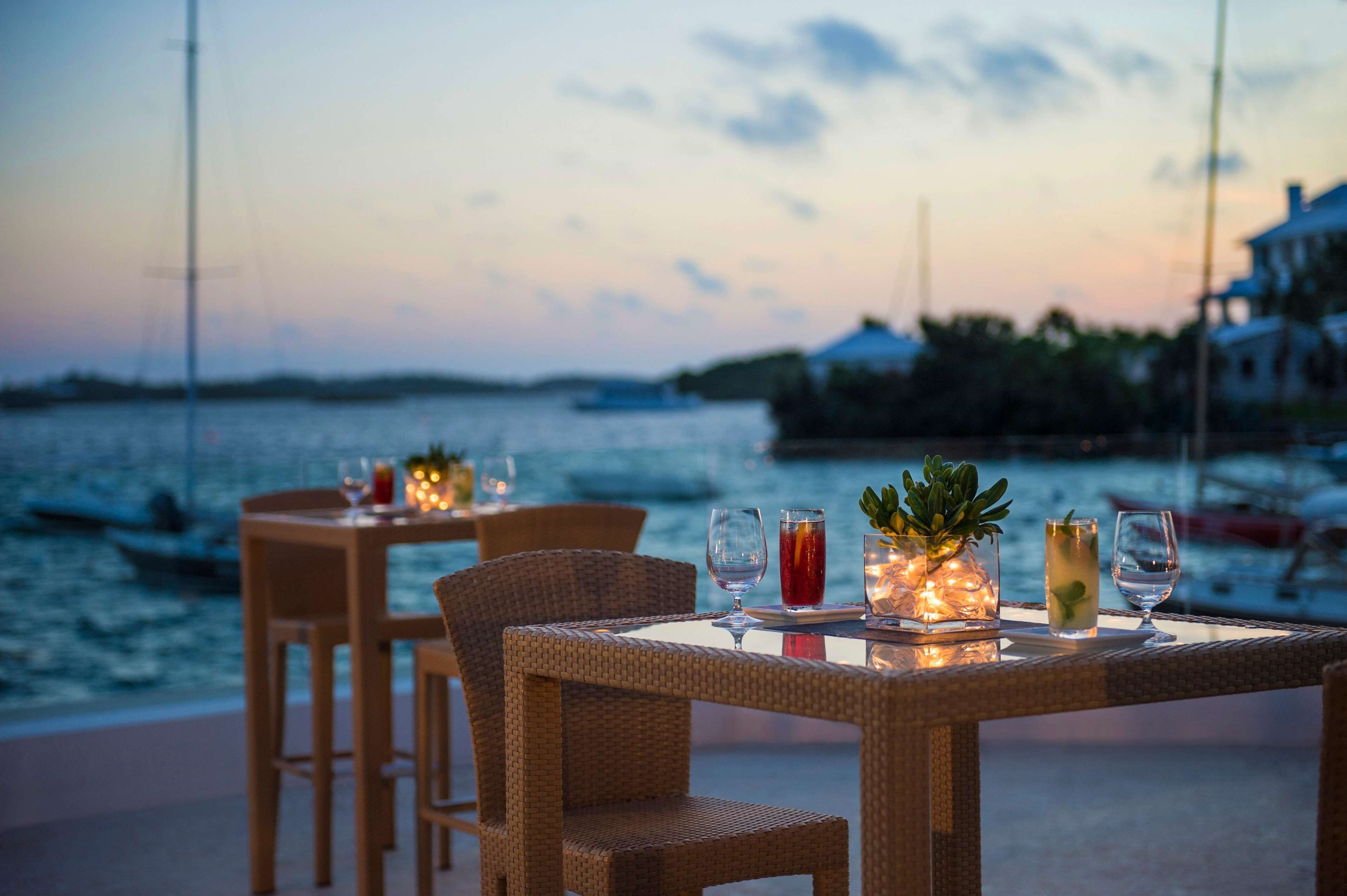 A dining table with chairs and a view of the sea at dusk.