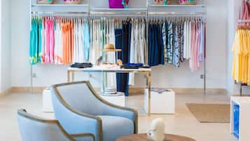 A boutique hotel room with a seating area, a table with a decorative item, and a clothing rack with various garments.