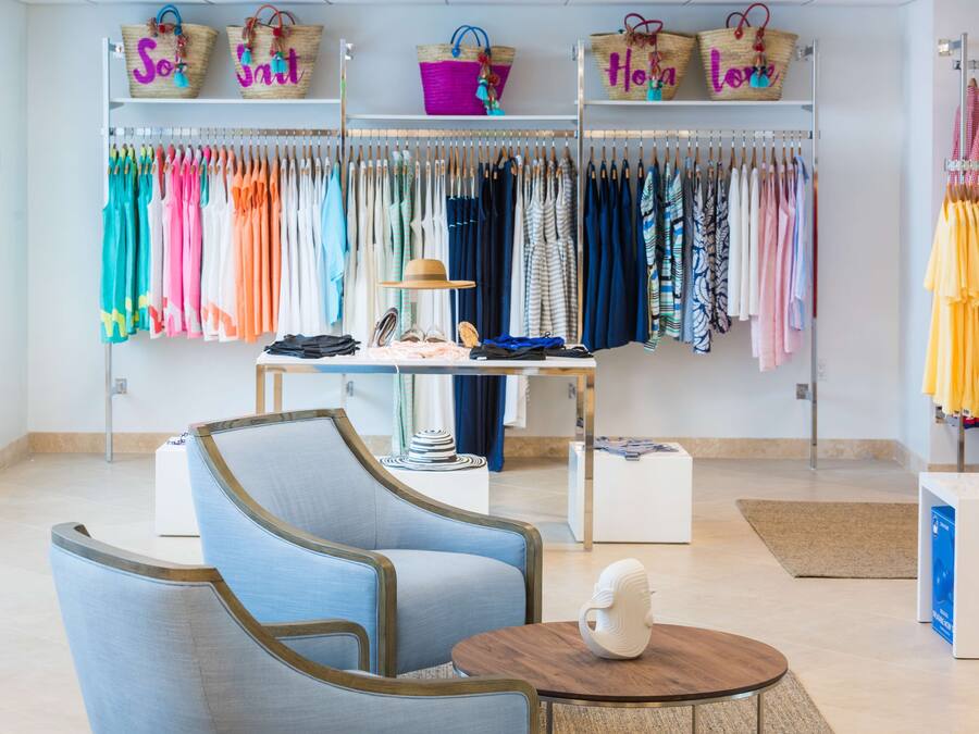 Une chambre d’hôtel de style boutique, dotée d’un coin salon, d’une table agrémentée d’un objet décoratif et d’un portant à vêtements avec divers articles d’habillement.