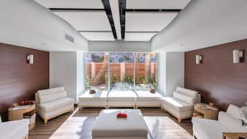 A modern living room with a glass partition, two sofas, a coffee table, and a wooden floor.