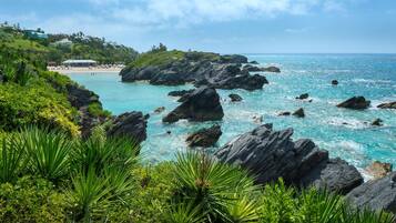 A coastal landscape with rocky outcrops, clear turquoise waters, and lush greenery.