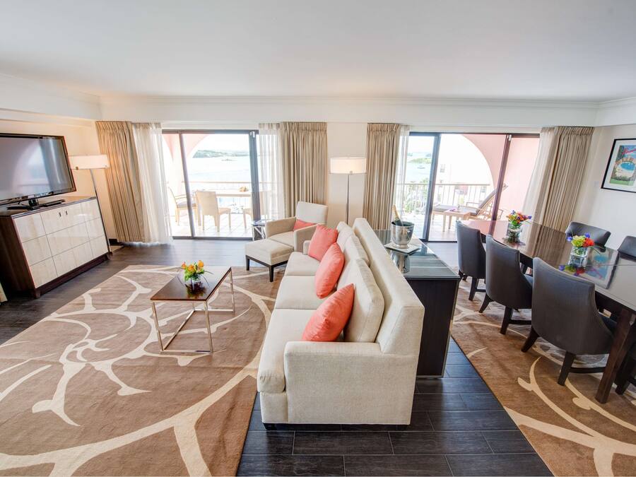 A hotel room with a sofa, TV, dining table, and chairs.