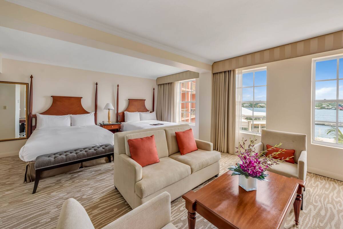 Ein Hotelzimmer mit Bett, Sofa, Esstisch und Blick aufs Meer.