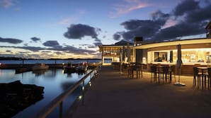 Un bar situé au bord de l’eau, avec une terrasse et vue sur le plan d’eau.
