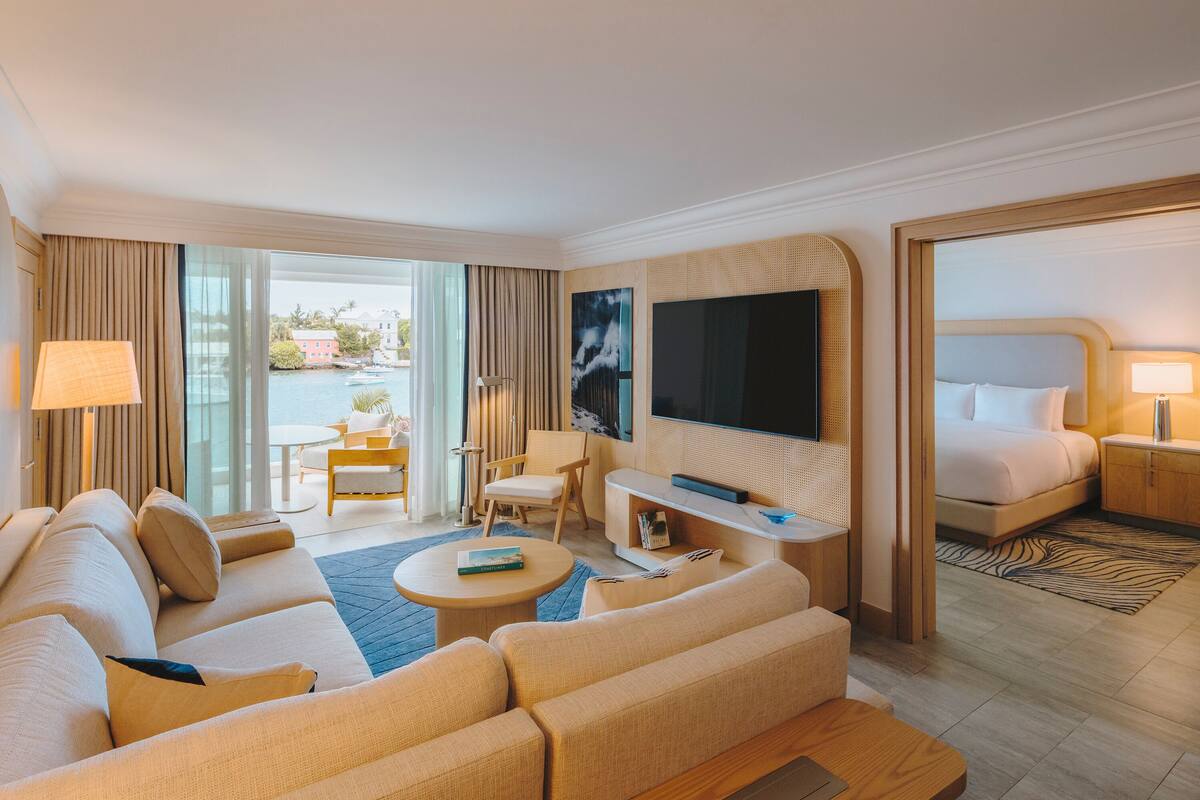 Ein Hotelzimmer mit einer Couch, einem Sessel, einem Fernseher und einem Bett.