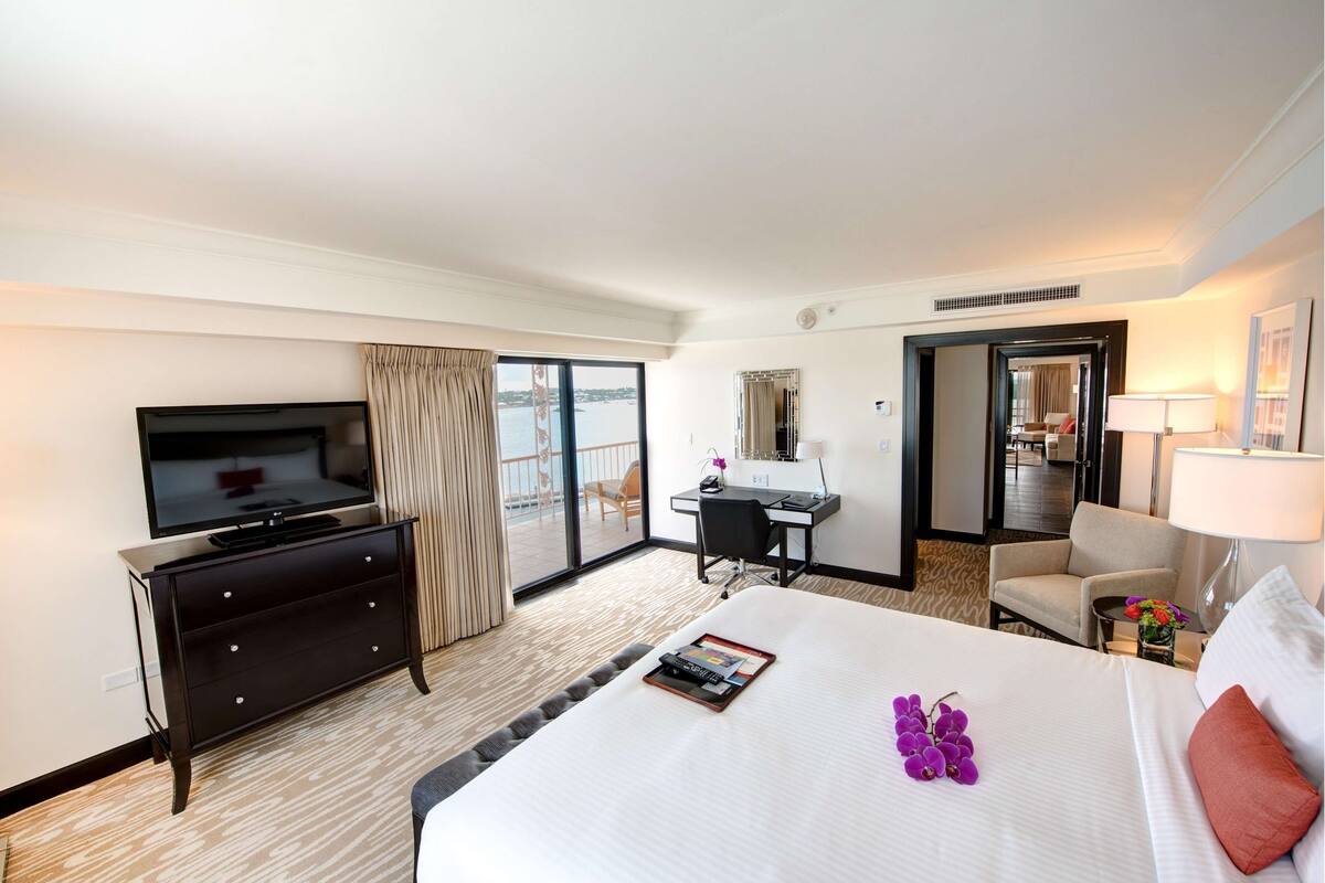 Ein Hotelzimmer mit einem großen Bett, einem Schreibtisch, einem Fernseher und Blick ins Freie.