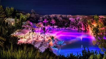 Un resort con piscina, palmeras y vista al océano.