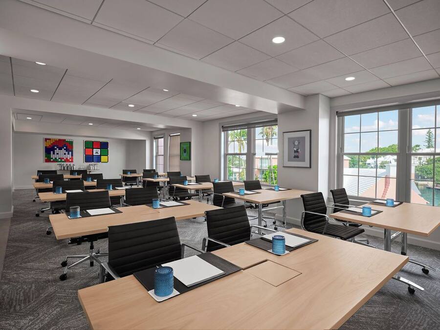 A conference room with multiple tables, chairs, and a large window offering a view of the outdoors.