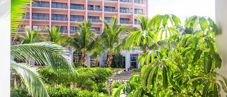 A multi-story hotel with balconies, surrounded by lush greenery and palm trees.