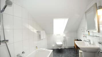 Une salle de bain moderne équipée d’une baignoire, d’une douche, de toilettes et d’un lavabo.