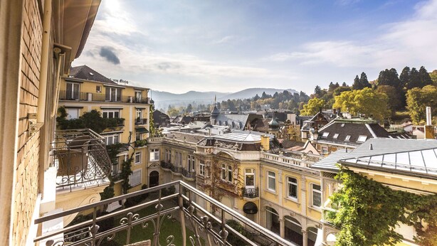 Ein Innenhof mit Gebäuden, einer Treppe und Blick auf ferne Hügel.