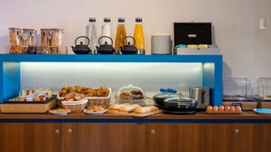 Um buffet de café da manhã com diversos alimentos, bebidas e utensílios de cozinha.