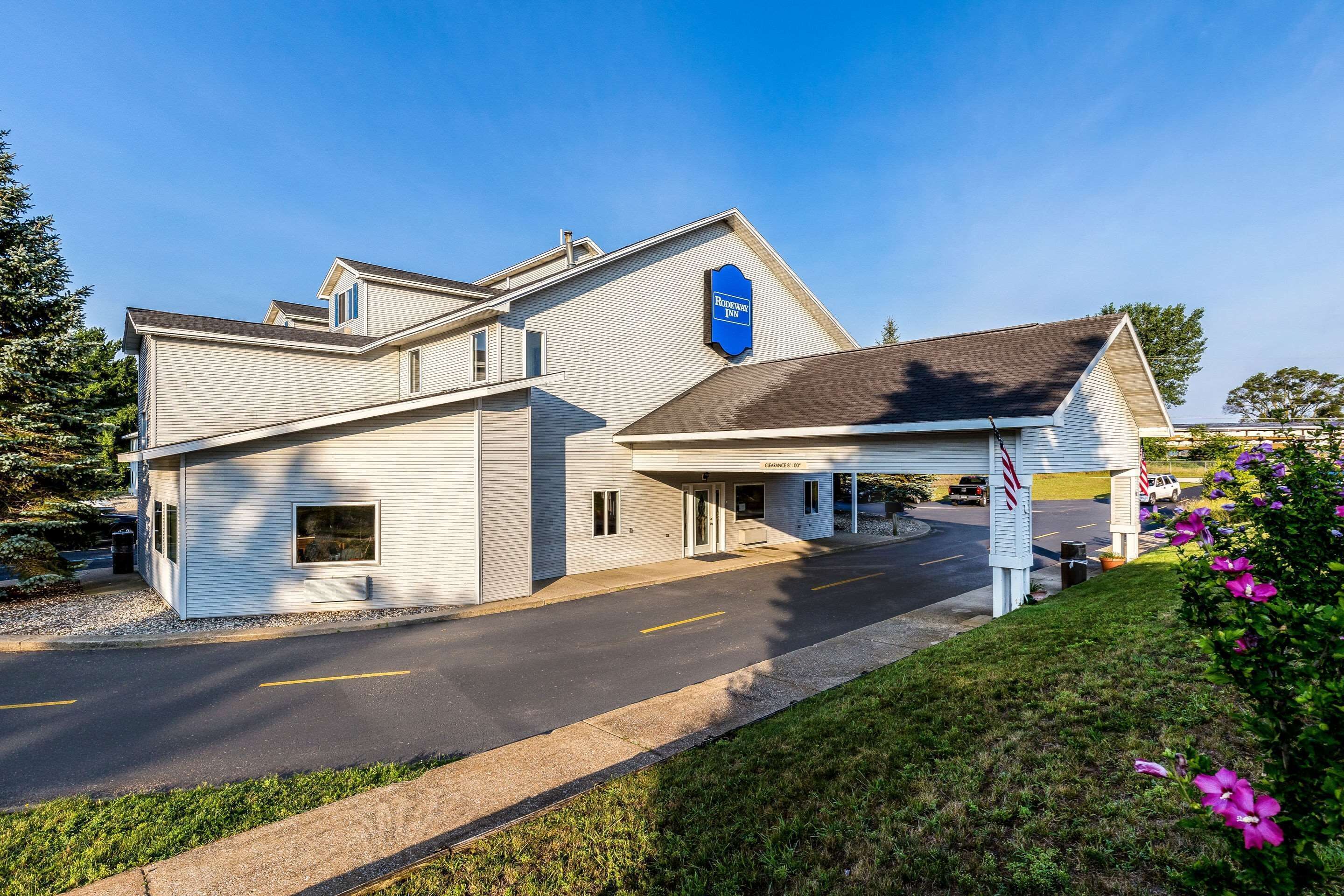 A hotel with a modern design, a covered parking area, and a well-maintained lawn.